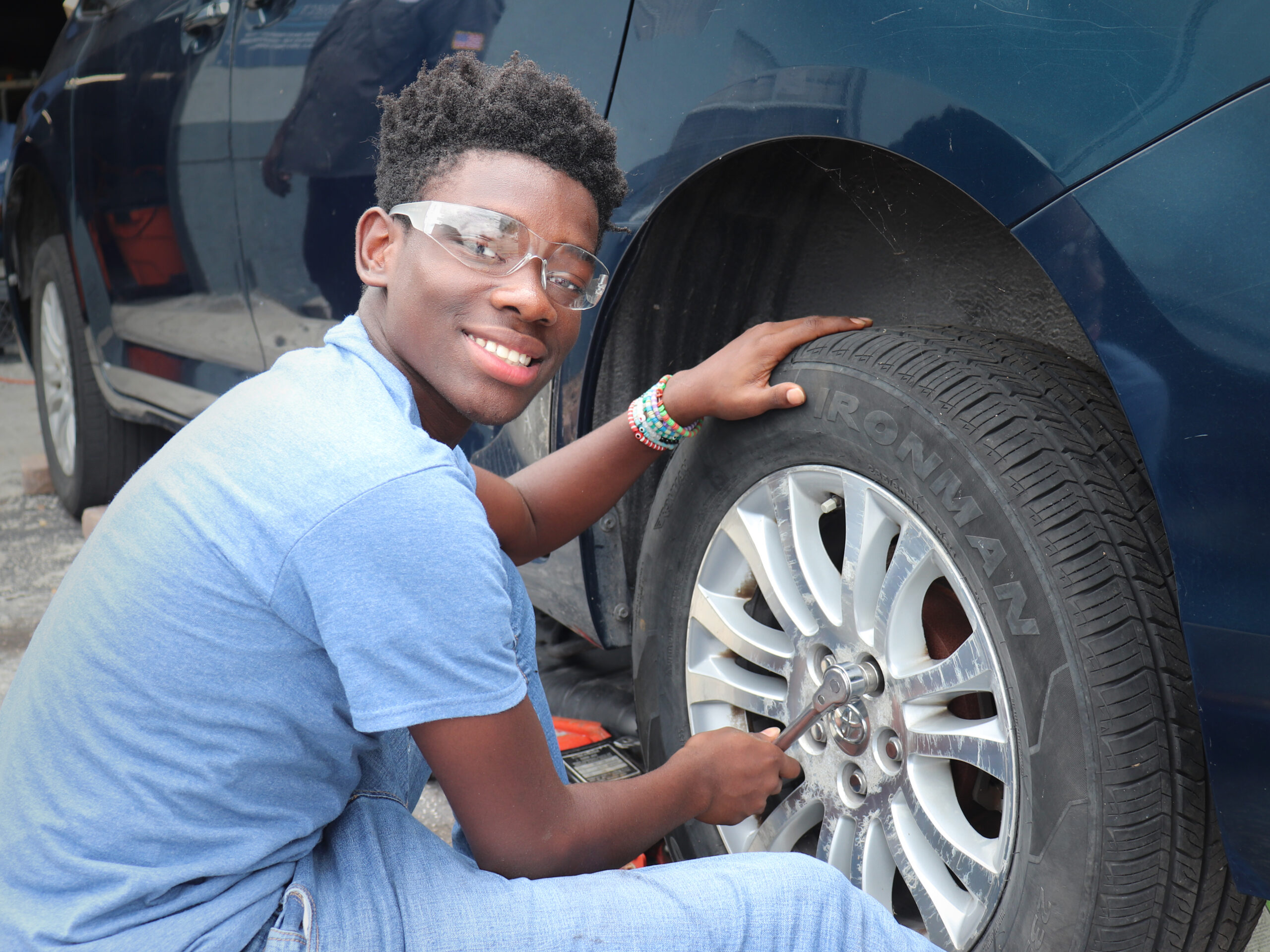 Project LIFT auto mechanic student in front of a tire