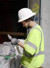 Electrical apprentice on job site reading building plans